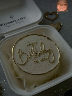 a birthday cake in a plastic container with the name happy birthday written on it and gold foil