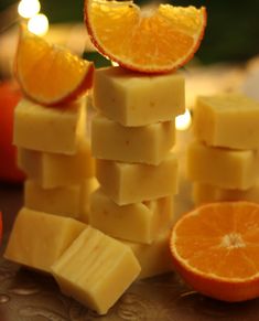 sliced oranges and pieces of cheese stacked on top of each other with candles in the background