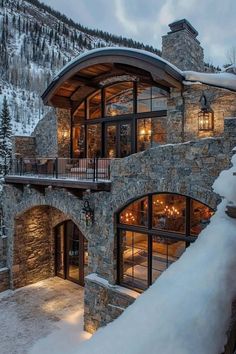 a large stone house surrounded by snow covered mountains