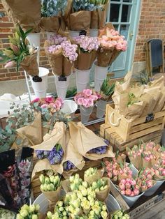 many different types of flowers on display at a flower shop with brown paper bags over them