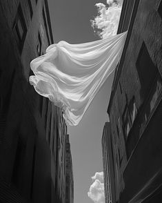 a white sheet is floating in the air between two buildings