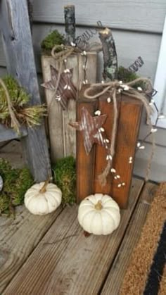 two white pumpkins sitting on top of a wooden crate next to other fall decorations