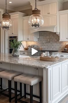 a large kitchen with white cabinets and marble counter tops, an island with stools