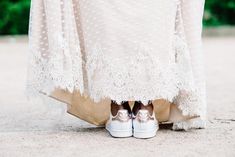 a woman in white dress and gold shoes standing on the ground with her legs crossed