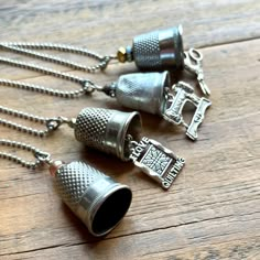 three silver thimbles on a wooden table with chains and pendants hanging from them