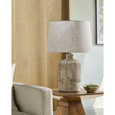 a table lamp sitting on top of a wooden table next to a chair and window