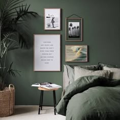 a bedroom with green walls and pictures on the wall above the bed, along with a small side table