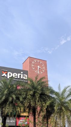 a tall building with a clock on it's side and palm trees in the foreground