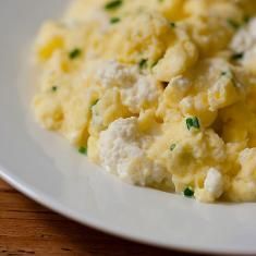 scrambled eggs with chives on a white plate