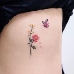 a woman's stomach with two flowers and a butterfly on the side, one flower is pink