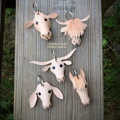 four cow heads are hanging on the side of a wooden board with metal clips attached to them