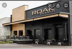 people are sitting at tables in front of a building that is black and has the word roak brewing co written on it