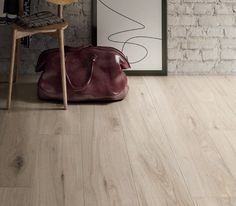 a brown bag sitting on top of a wooden floor next to a chair and brick wall