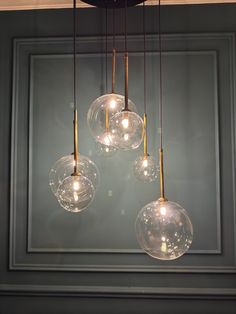 three clear glass globes hanging from a chandelier in a room with gray walls