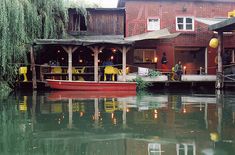 a boat is docked in the water next to a building with people sitting on it