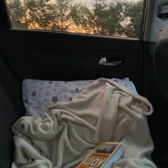 the back seat of a car with a blanket on it and a book in the backseat