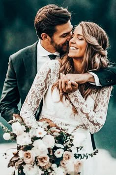 a bride and groom embracing each other in front of flowers