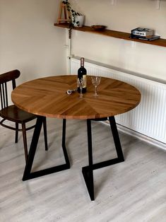 a wooden table with two chairs and a bottle of wine on the table next to it