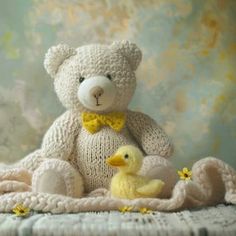 a white teddy bear sitting on top of a blanket next to a yellow rubber duck