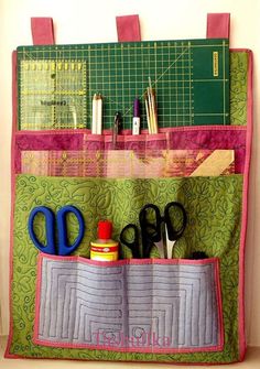 a bag with scissors and other crafting supplies in it, hanging on a wall