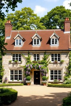 Stone cottage with wisteria framing the entrance. Explore the quirky charm, secret staircases, and unintentional labyrinths of British country houses, where historical oddities meet modern mishaps in the most delightful way.