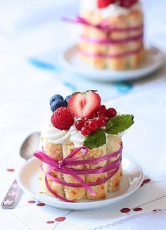 a small cake with berries and whipped cream on top is sitting on a white plate