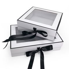 two white boxes with black ribbons tied around the edges, one is open and the other is closed