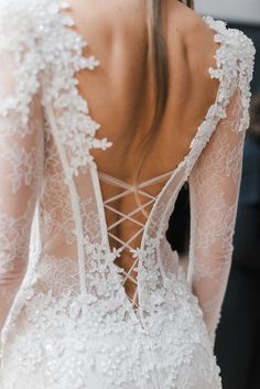 the back of a woman's wedding dress with sheer lace and beading on it