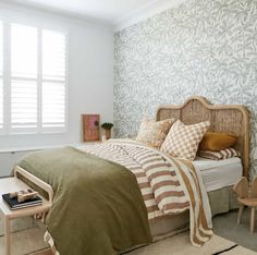 a bed room with a neatly made bed next to a chair and table in front of a window