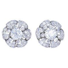 A beautiful pair of vintage platinum diamond earrings from the roaring 1930s. While designed as classic cluster earrings, this Art Deco inspired platinum diamond pair features unique details. Resembling a flower, each earring features in the center an antique cushion cut diamond, also called Old Mine cut. These two diamonds come with GIA Diamond Grading Reports (see pictures 6 and 7). The "flower’s petals” are skillfully crafted out of folded platinum and embellished with diamonds. Between the p Luxury Platinum Cluster Earrings With Diamond Cut, Luxury Single Cut Diamond Cluster Earrings For Engagement, Luxury Silver Platinum Cluster Earrings, Luxury Classic Lab Grown Diamond Cluster Earrings, Luxury Elegant Lab-grown Diamond Cluster Earrings, Timeless Luxury Diamond White Cluster Earrings, Luxury Timeless Diamond White Cluster Earrings, Antique Cushion Cut Diamond, Antique Cushion Cut