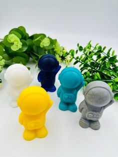 four small plastic toys sitting next to green plants