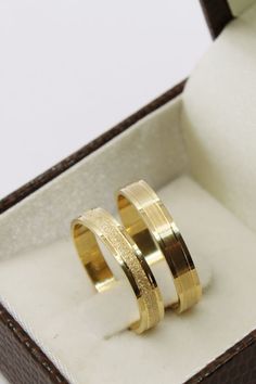 two gold wedding rings sitting in a box