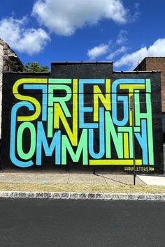 a large mural on the side of a building that says strength community in bright colors