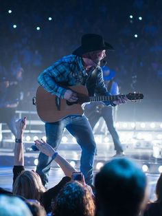 a man with a guitar in front of an audience at a music concert on stage