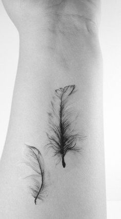 a black and white photo of a feather tattoo