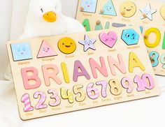 a stuffed animal sitting next to two wooden numbers and shapes puzzles on a white surface