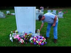 a man placing flowers on the headstone of a grave