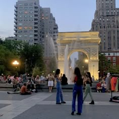 people are standing in front of a fountain at dusk