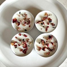 four desserts are sitting on a plate with white icing and dried flowers in them