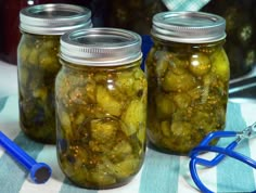 three jars filled with pickles sitting on top of a checkered table cloth next to a stethoscope