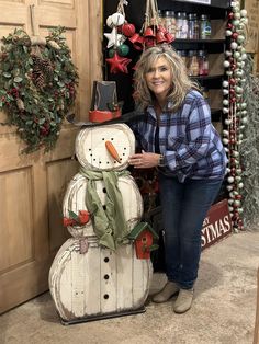 a woman standing next to a wooden snowman