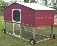 a red chicken coop on wheels in the grass