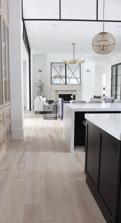 an open kitchen and living room with white walls, wood flooring and black cabinets