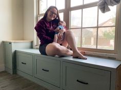 a woman sitting on a window sill holding a baby