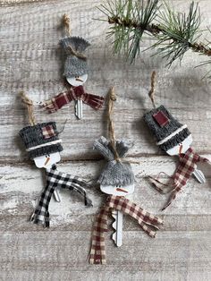 christmas ornaments made out of clothes hanging on a wooden board with pine needles and twine