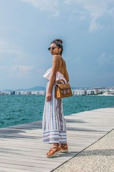 a woman standing on a pier next to the ocean with her back to the camera