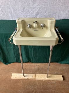 a white sink sitting on top of a wooden stand next to a green tablecloth