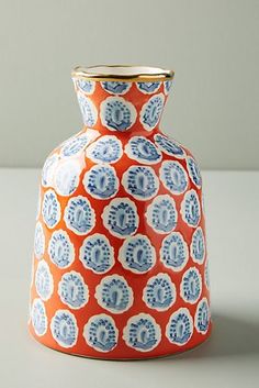 an orange and blue vase sitting on top of a table