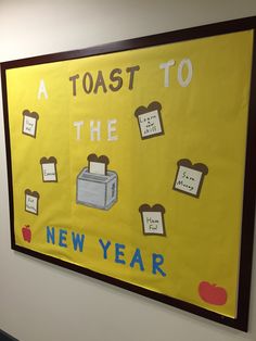 a yellow poster with toast to the new year written on it in front of a white wall