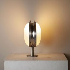 a table lamp sitting on top of a white block next to a light fixture with a round glass shade